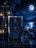 Nazam Perfumes Midnight Blue 25ml premium Arabic attar bottle with a silver dome cap next to its deep blue geometric presentation box on a reflective table under a full moon backdrop.
