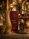 Nazam Perfumes Onyx Oud 25ml premium Arabic attar bottle with a gold dome cap next to its burgundy and gold presentation box on a reflective table.